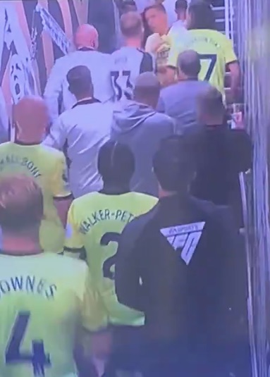 a group of men in yellow jerseys are walking down a hallway .