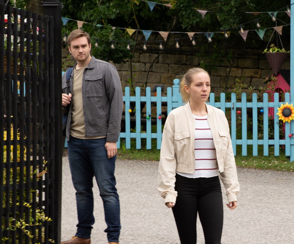 a man and a woman standing in front of a blue picket fence