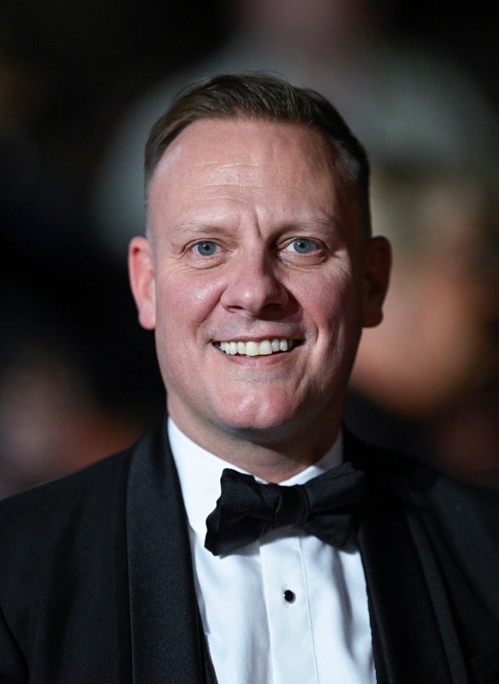 a man in a tuxedo and bow tie smiles for the camera