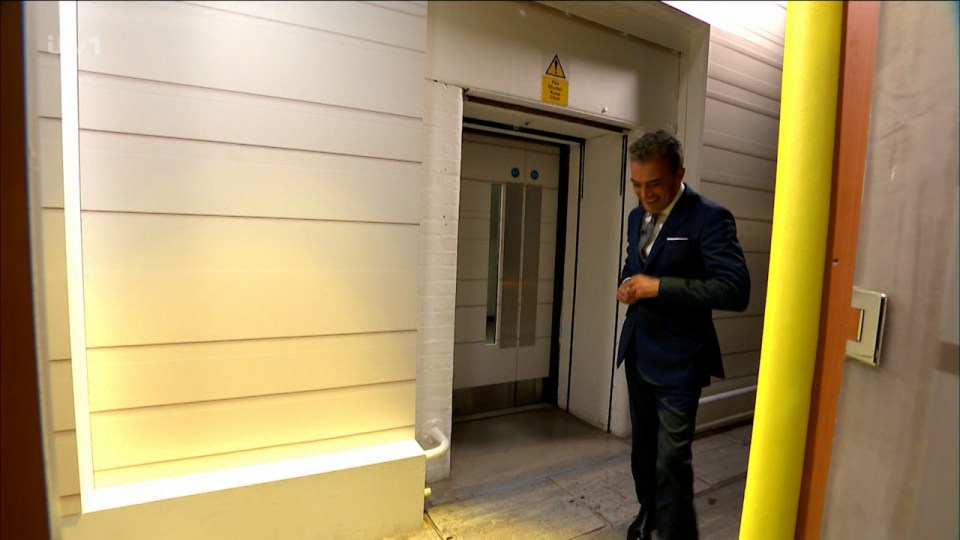 a man in a suit stands in front of an elevator with a yellow warning sign on the door