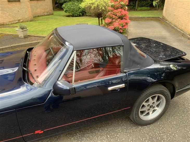 a black sports car with a black top is parked in a driveway