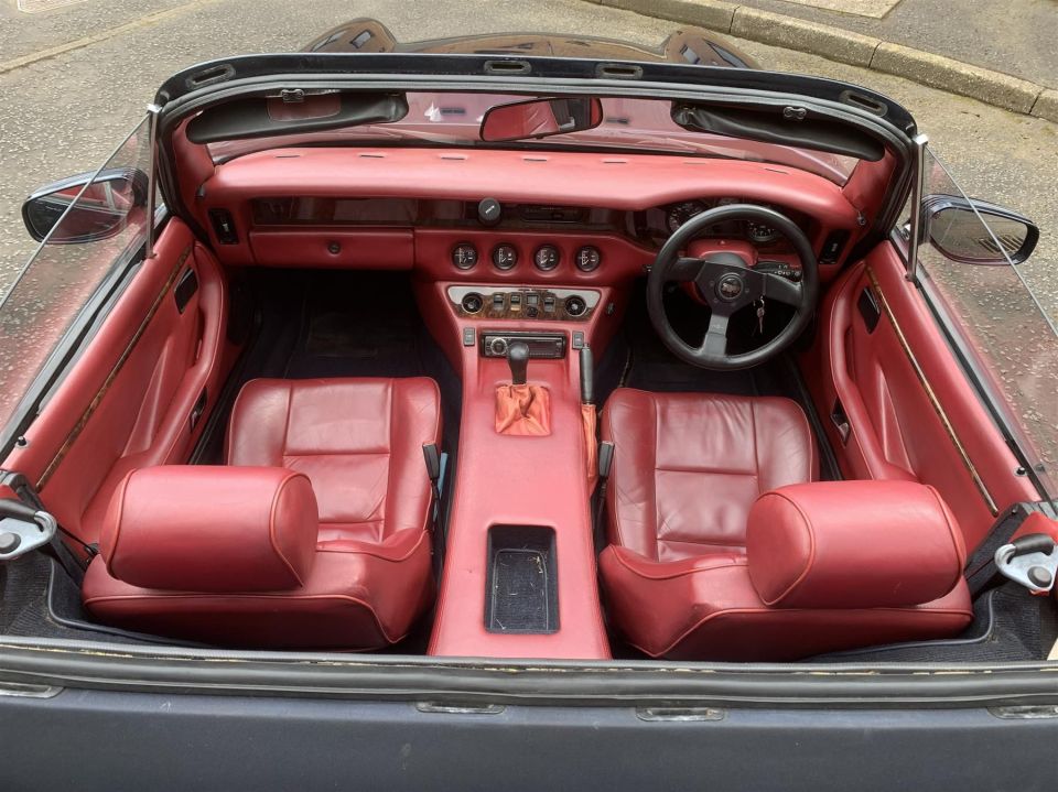 the inside of a car with red seats and a steering wheel