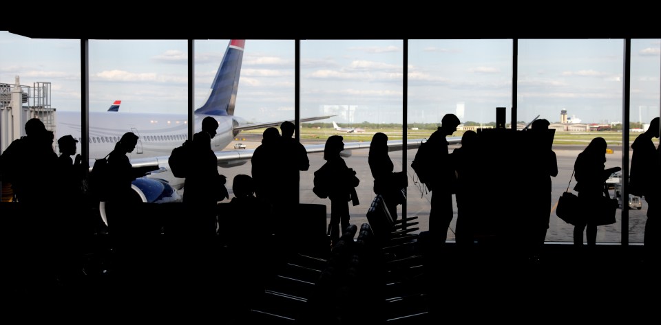 a group of people standing in front of a window with a delta airlines plane in the background