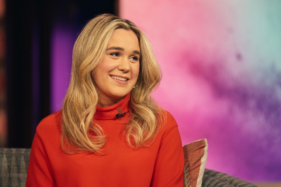 a woman in a red sweater is smiling while sitting on a couch