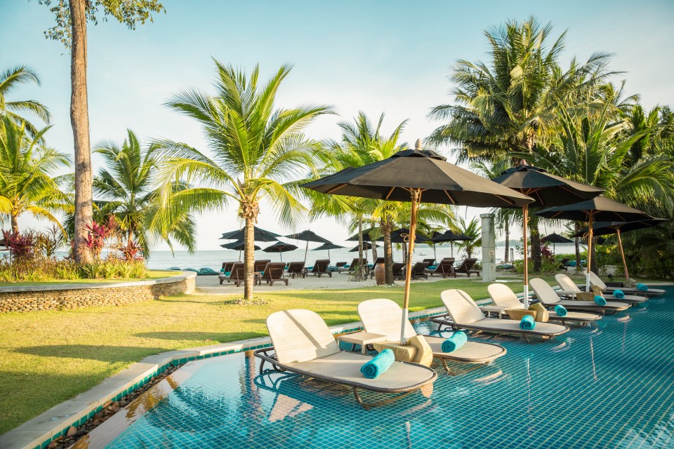 a swimming pool surrounded by lounge chairs and umbrellas