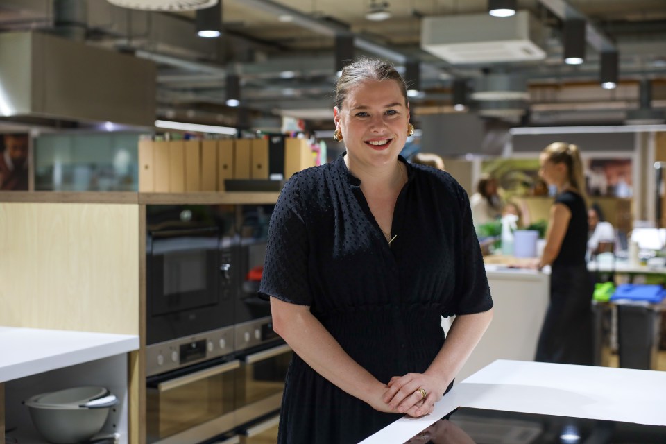 a woman in a black dress is standing in a kitchen