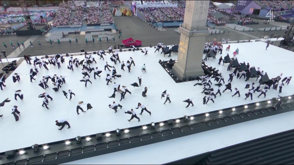 a large group of people are dancing in front of an obelisk