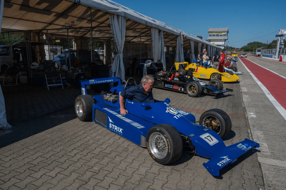 a man sits in a blue racing car with the number 17 on it