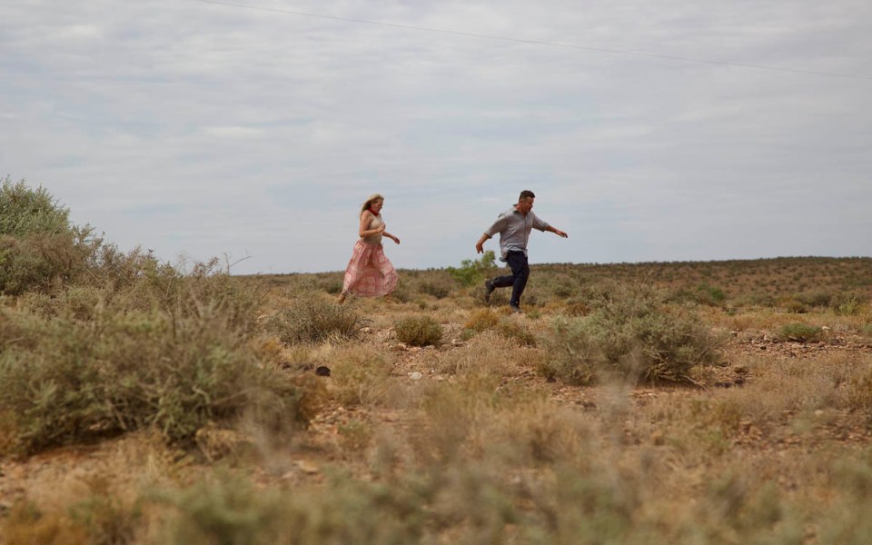 a man and a woman are running in the desert