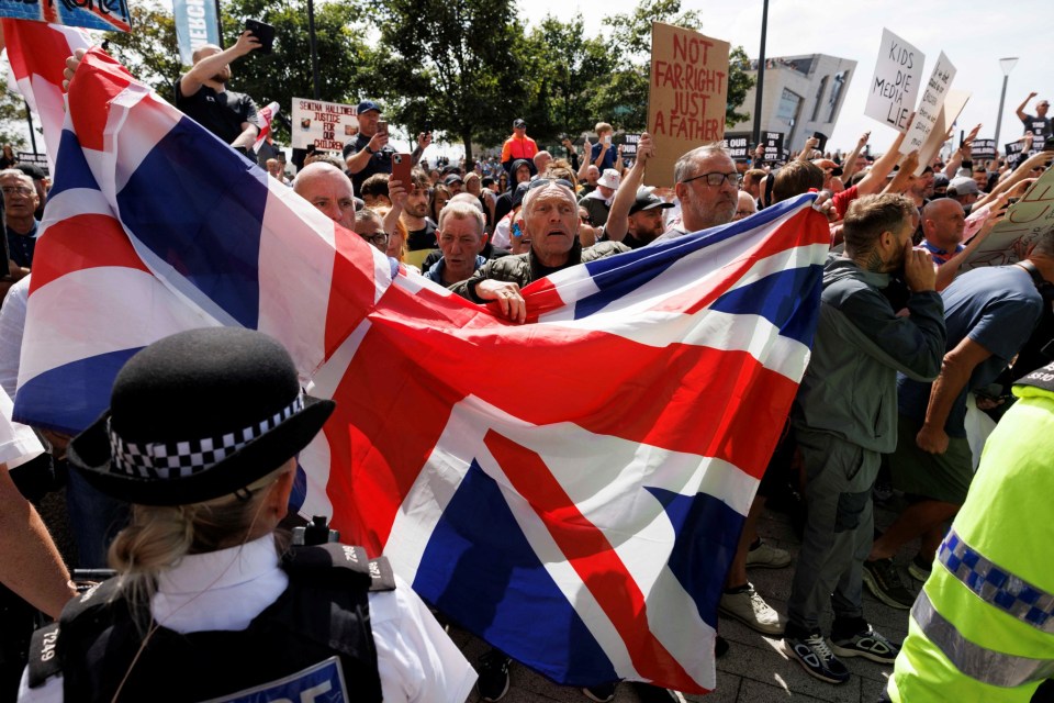 Far right protestors shout behind police a cordon in Liverpool, Britain, August 3, 2024. REUTERS/ Belinda Jiao