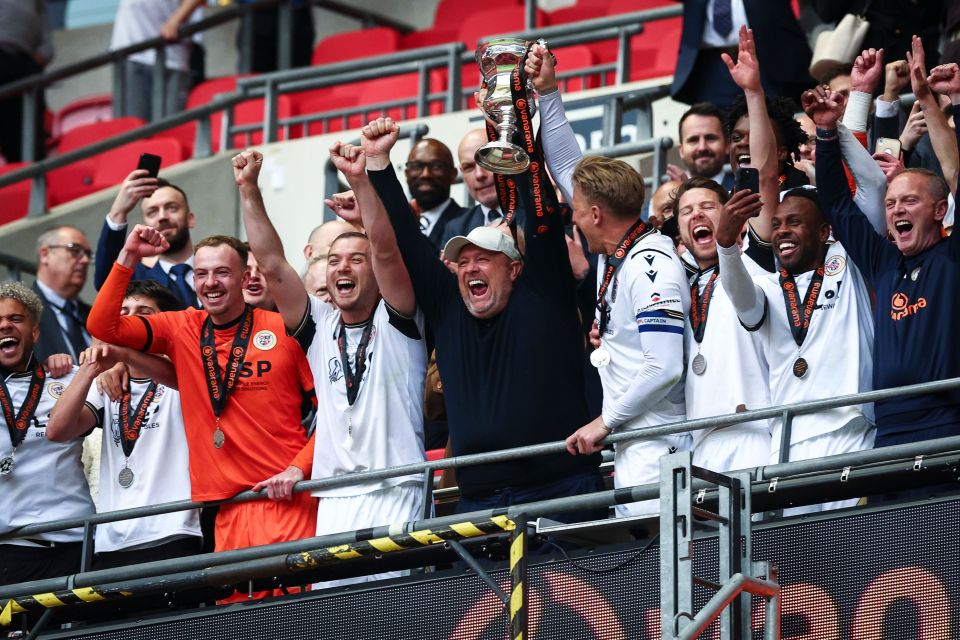 Andy Woodman and his Bromley team hold aloft the National League play-off winners trophy at Wembley after winning promotion to the EFL for the first time