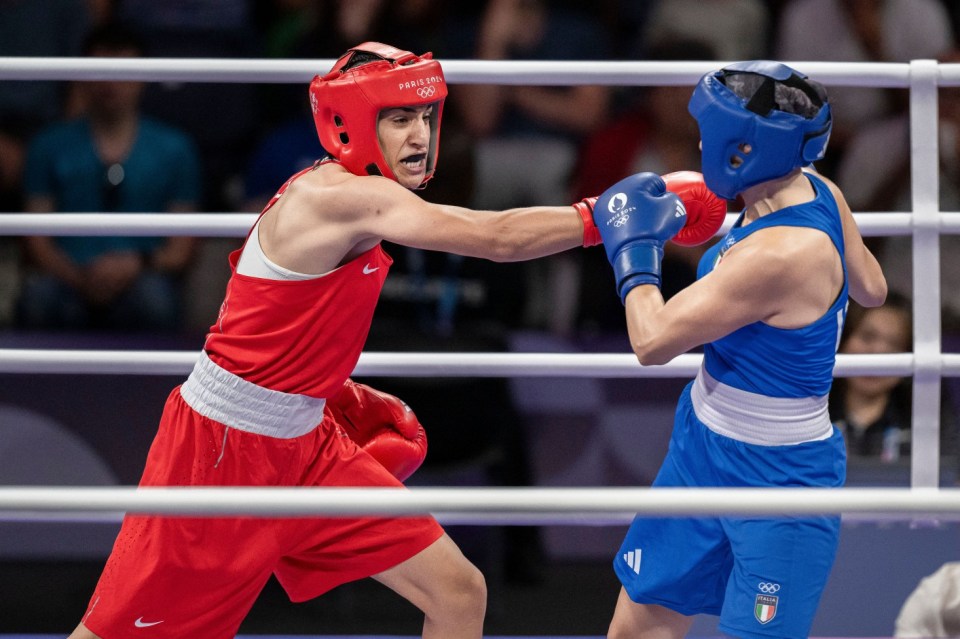 two boxers in a ring with one wearing a red helmet that says tokyo 2020