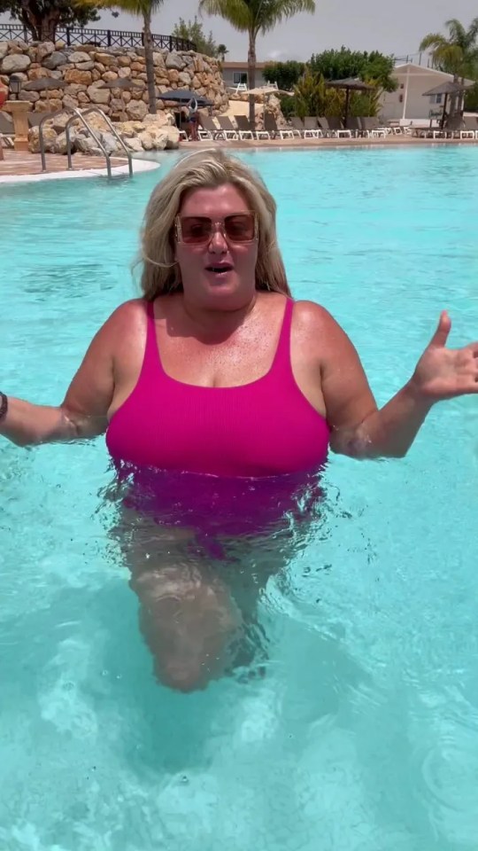 a woman in a pink swimsuit is standing in a swimming pool .