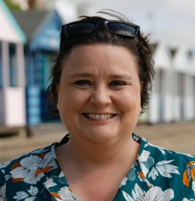 a woman wearing sunglasses and a floral shirt is smiling for the camera .