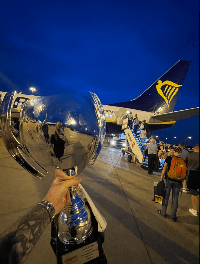 a person holding a trophy in front of a ryanair plane