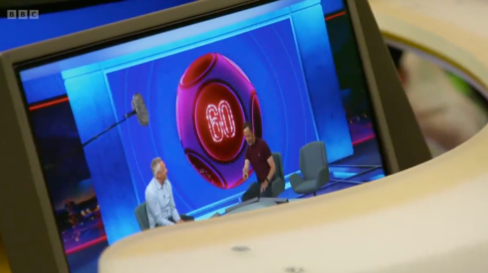 two men sit in front of a screen that says bbc