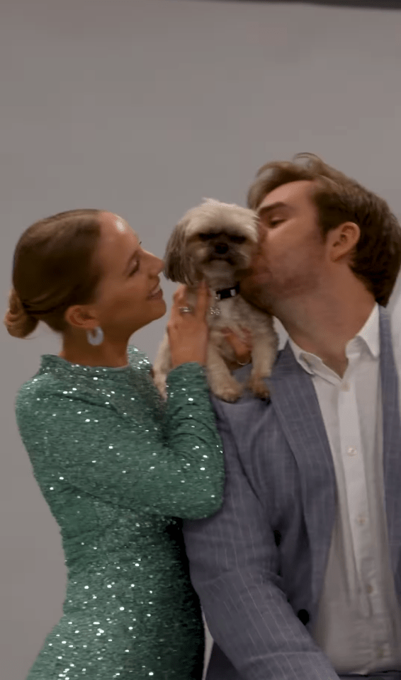 a man kisses a woman on the cheek while holding a small dog