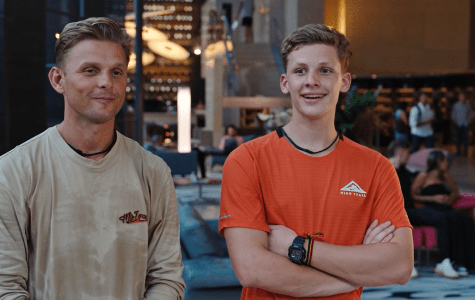 a man wearing a nike trail shirt stands next to another man