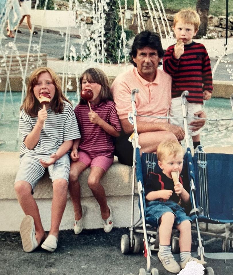 a man and three children are eating ice cream in front of a fountain