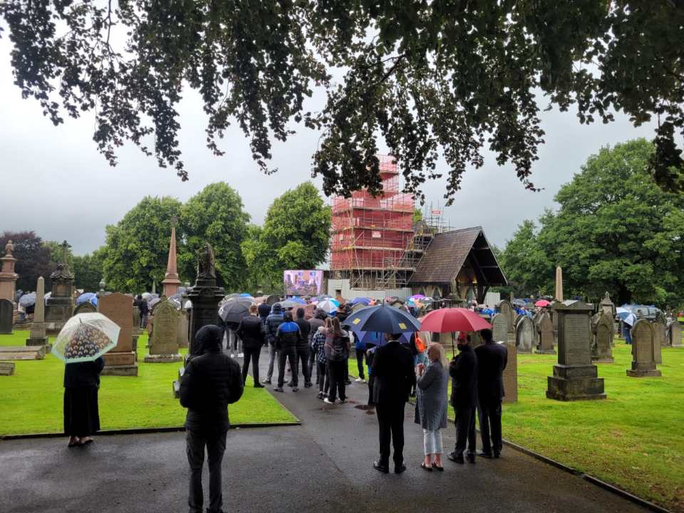 a group of people holding umbrellas in a cemeteryndres