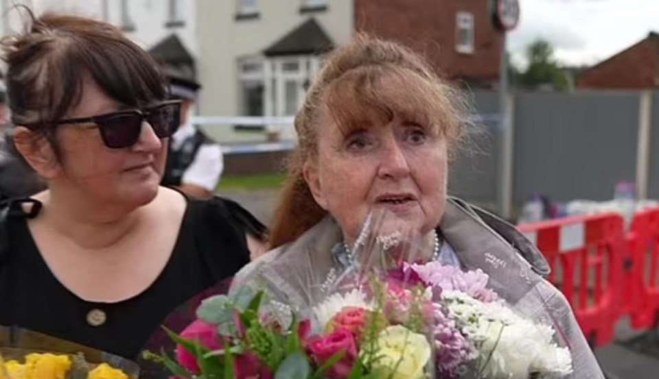 a woman is holding a bouquet of flowers while standing next to another woman .