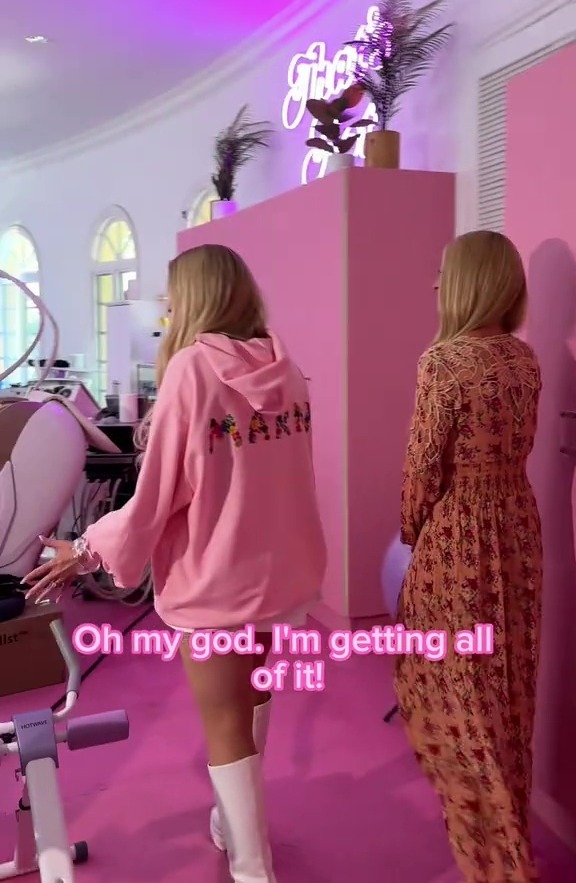 a woman wearing a pink hoodie says oh my god i 'm getting all of it