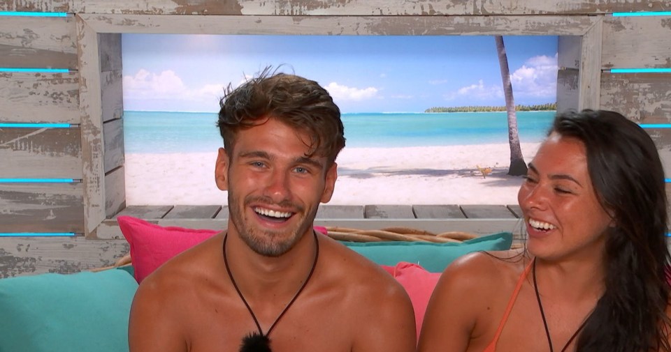 a man and a woman are smiling in front of a beach scene