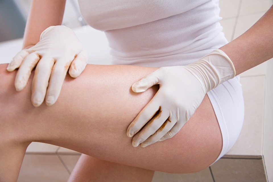 a woman wearing rubber gloves holds her leg