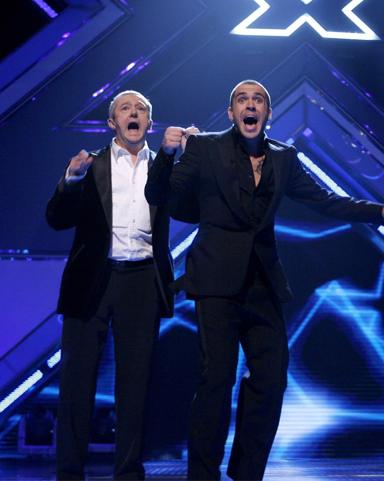 two men stand on a stage in front of a sign that says x