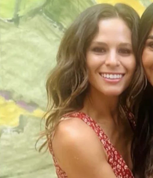 a woman in a red dress is smiling for the camera while standing next to another woman .