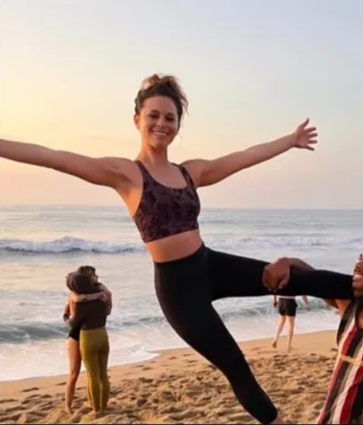 a woman is standing on a beach with her arms outstretched .