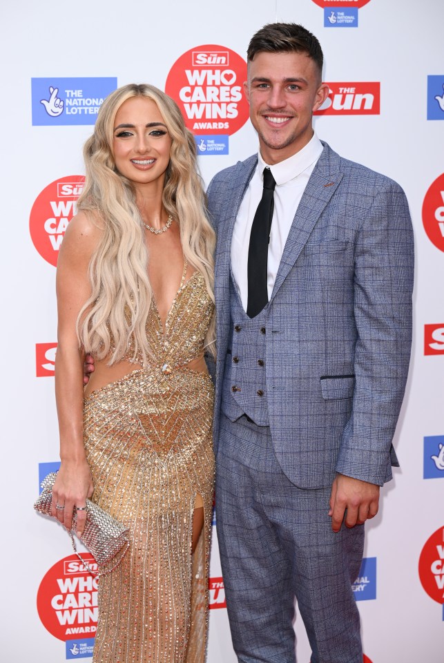 a woman in a gold dress and a man in a suit are posing for a picture at the sun who cares wins awards