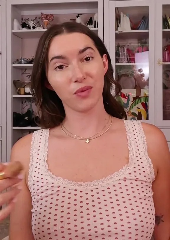 a woman in a white tank top is standing in front of a closet