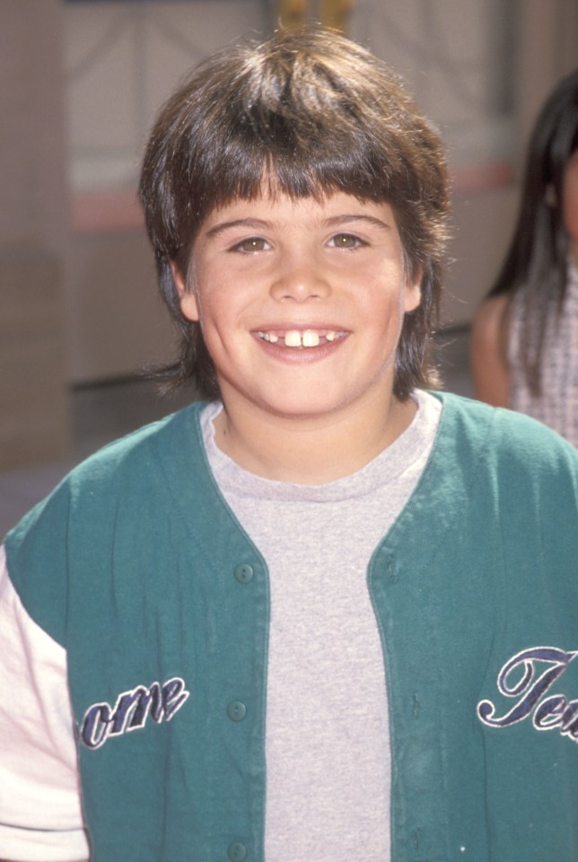 a young boy wearing a green jacket with the word one on it