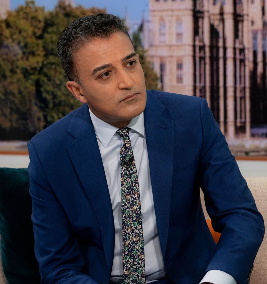 a man in a blue suit and tie sits on a couch