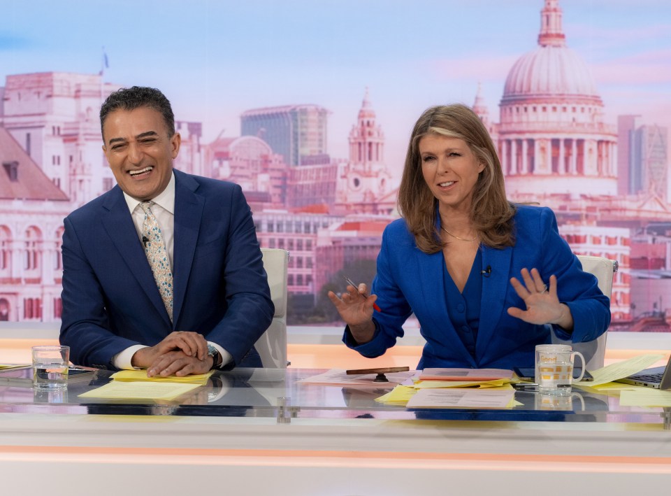 a man in a suit and tie and a woman in a blue suit are sitting at a desk