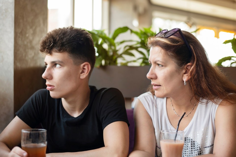 a woman and a boy sit at a table with drinks