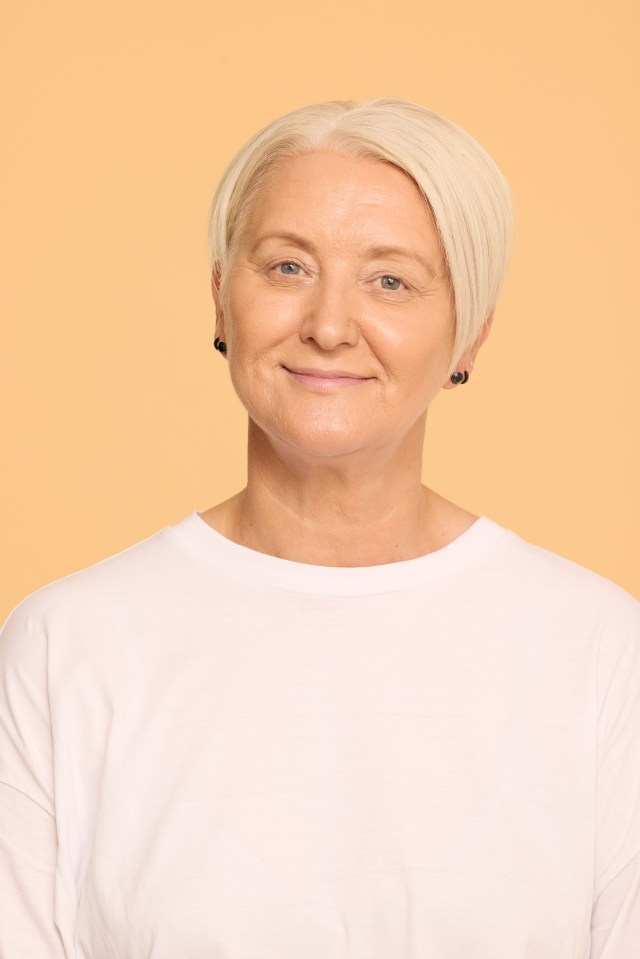 a woman wearing a white shirt and black earrings smiles for the camera