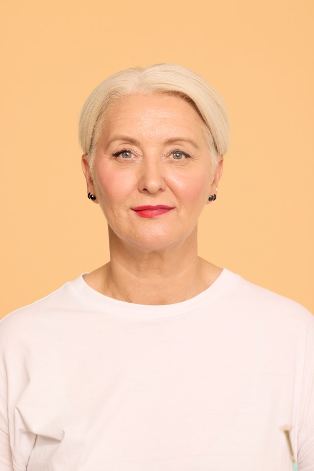 a woman wearing a white shirt and black earrings looks at the camera