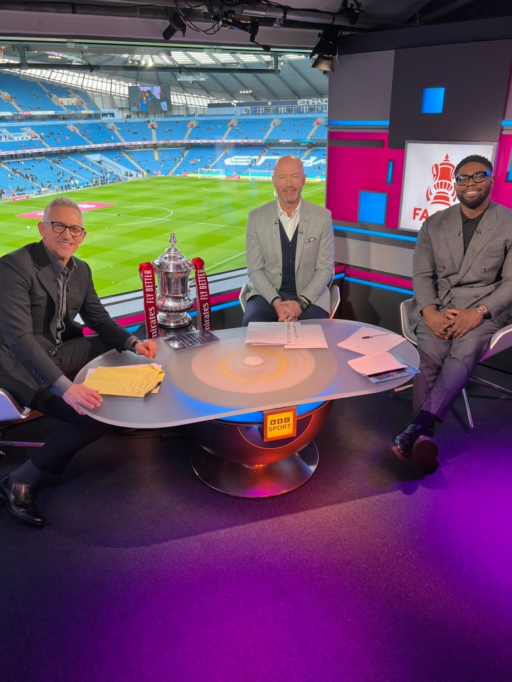 three men sit around a table with a trophy on it that says rugby league