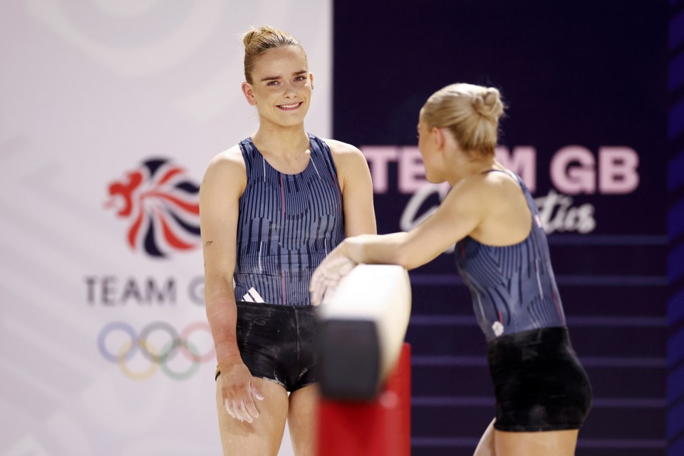 two female gymnasts are standing in front of a sign that says team gb