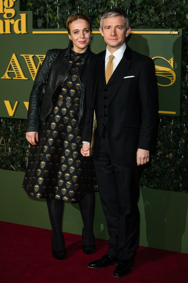 a man and a woman are standing on a red carpet in front of a sign that says awards