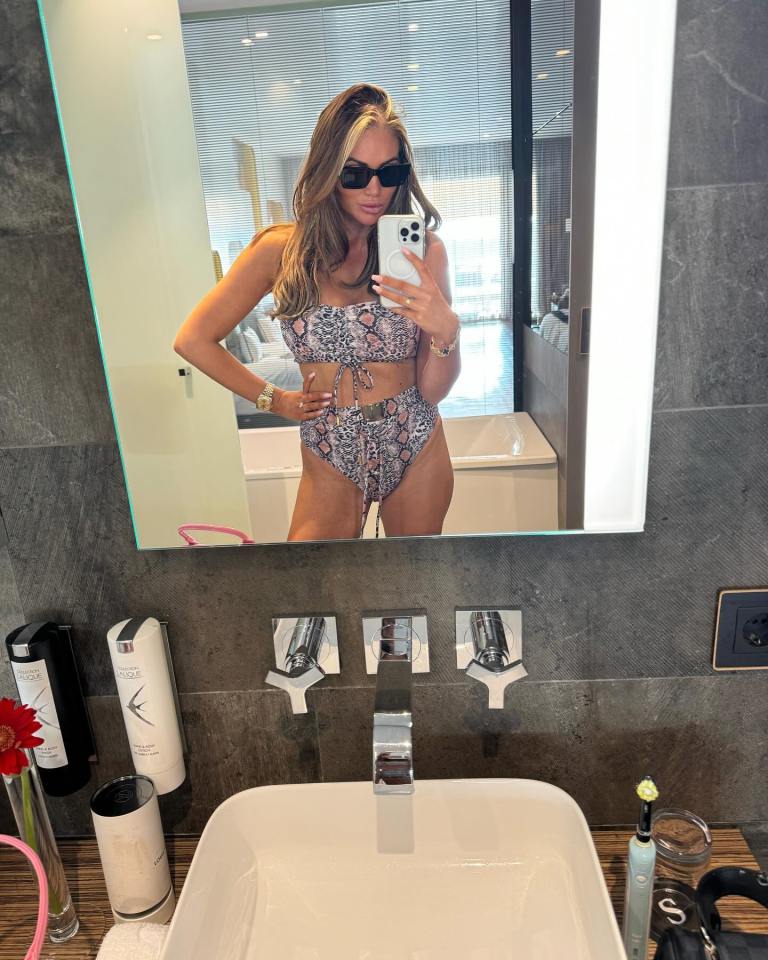 a woman in a bikini takes a picture of herself in a bathroom mirror