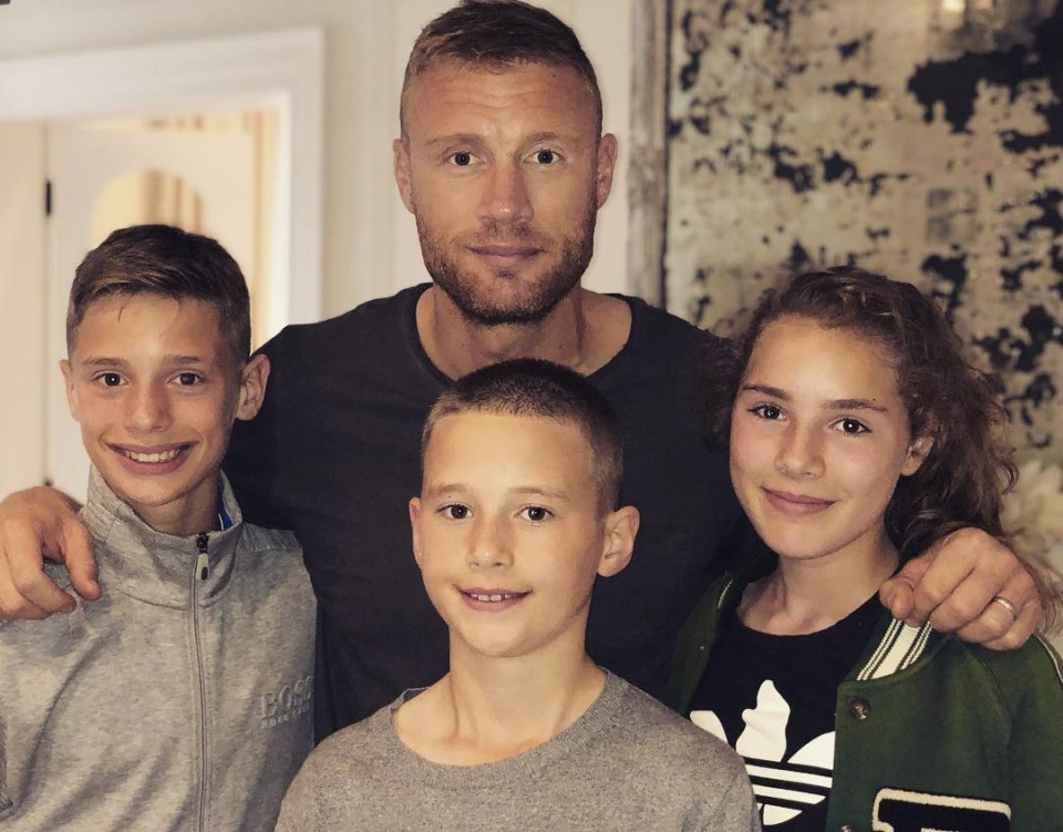 a man and three children pose for a picture and one of the children is wearing an adidas jacket