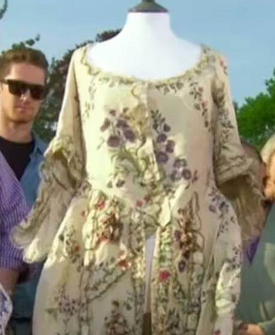 a woman is standing next to a mannequin wearing a floral dress .