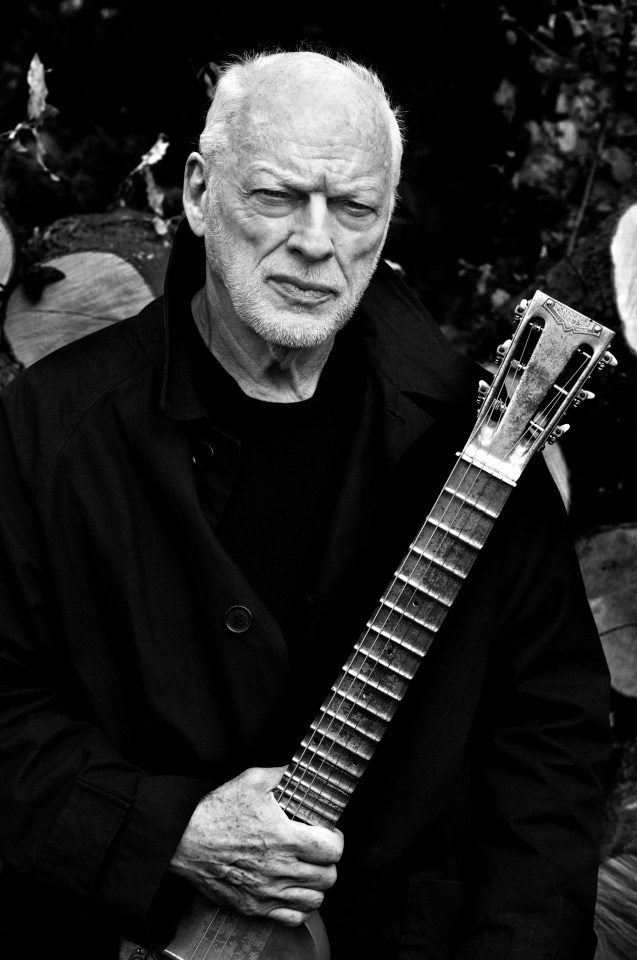 a man in a black coat is holding a guitar