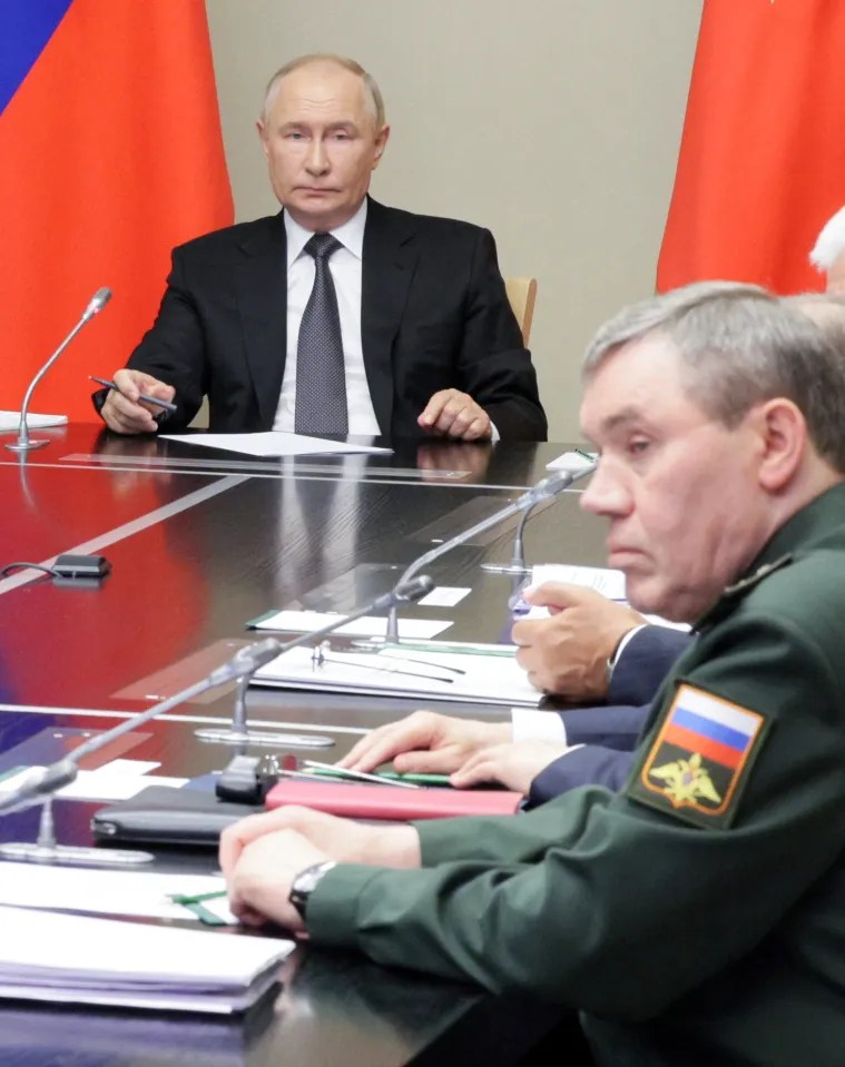 a man in a suit and tie sits at a table with other men