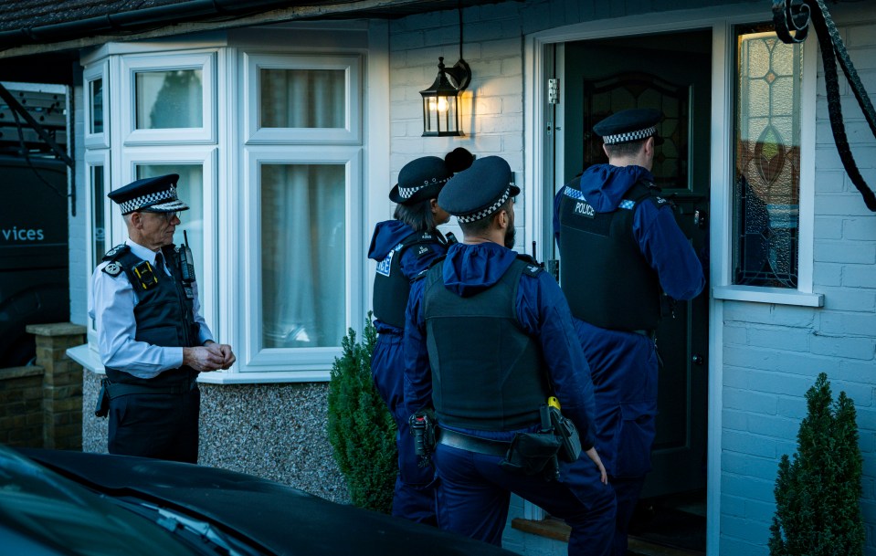 a group of police officers standing outside of a house