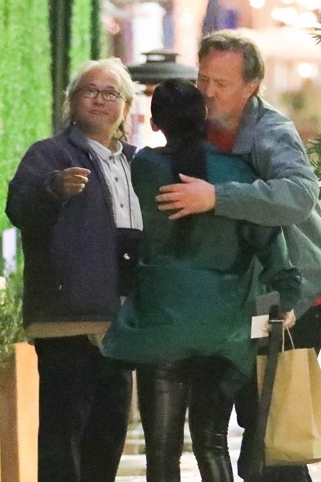 a woman in a green jacket is being hugged by two men