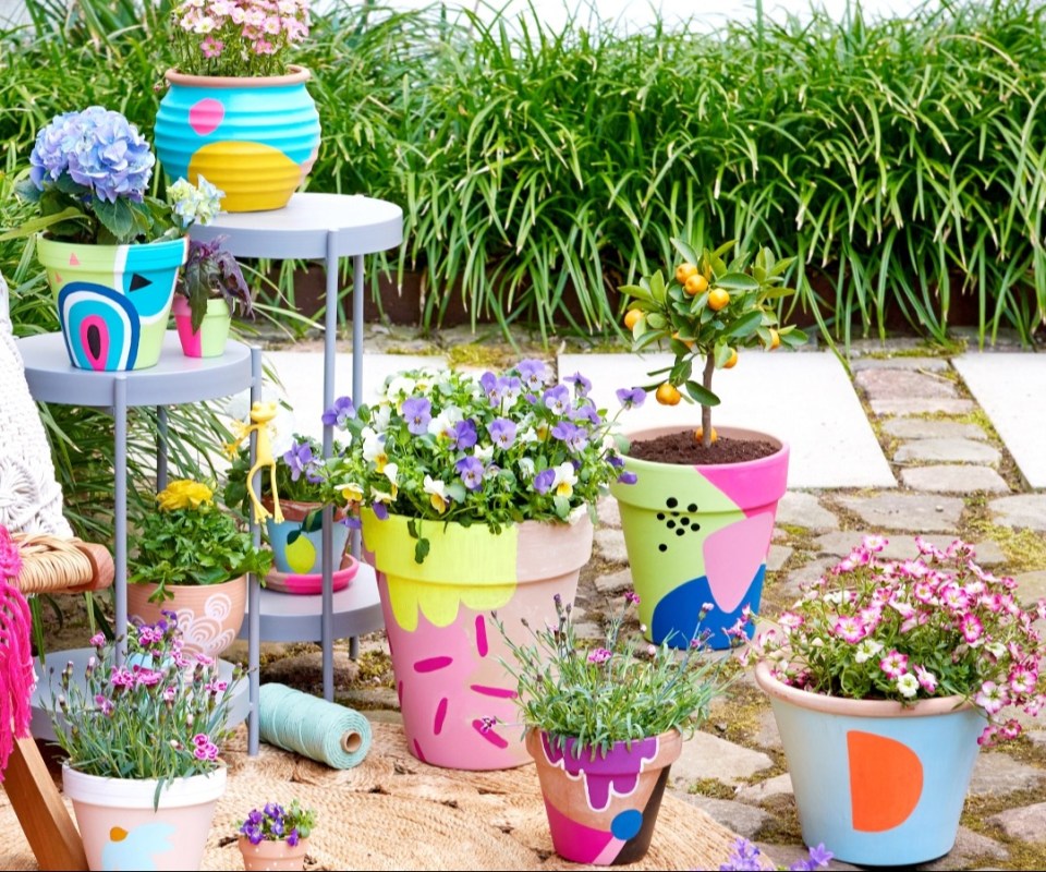 a bunch of painted pots with flowers in them